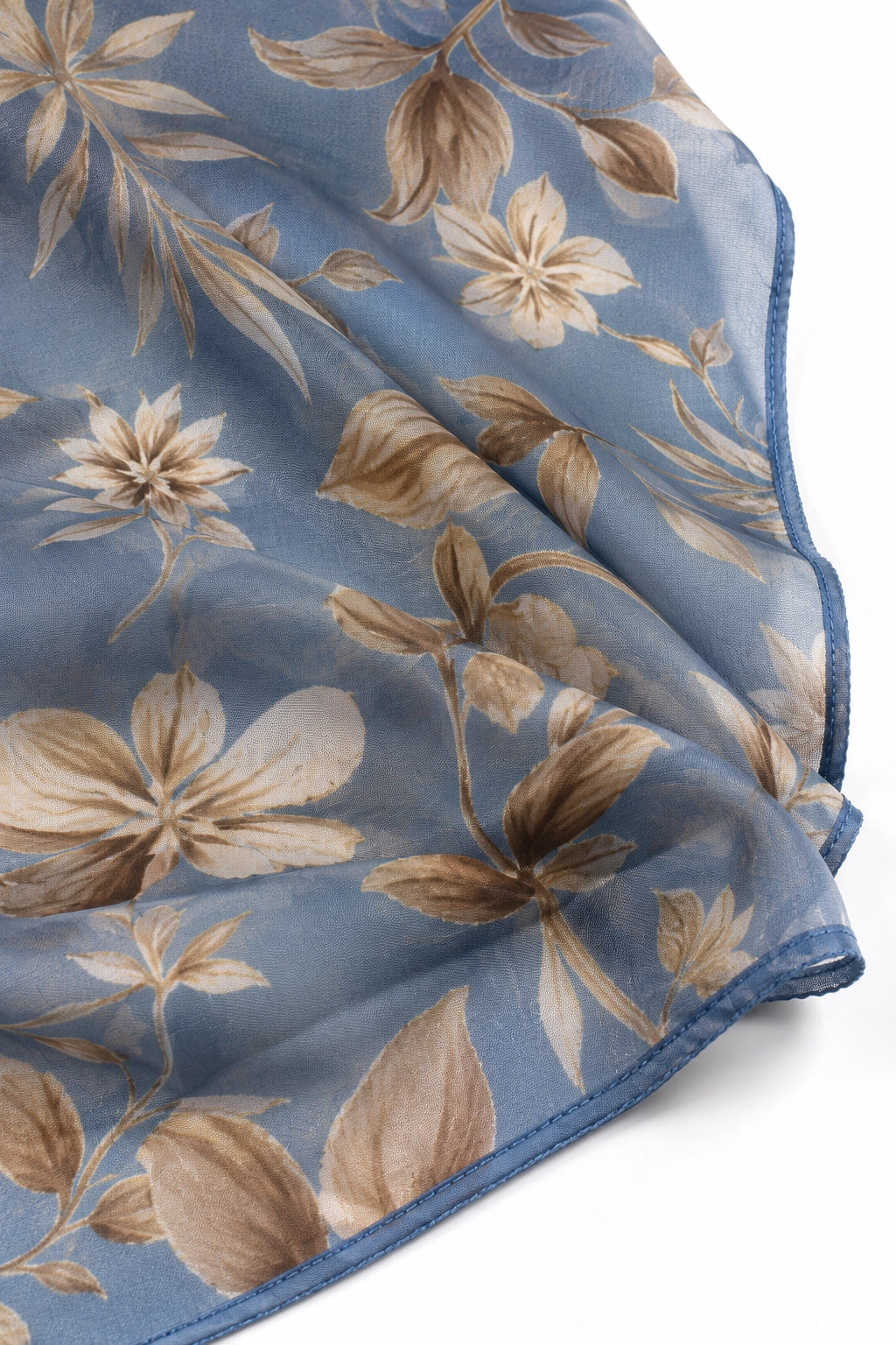 A close-up of a sheer blue scarf with a beige and brown floral print, folded to show its texture and border.