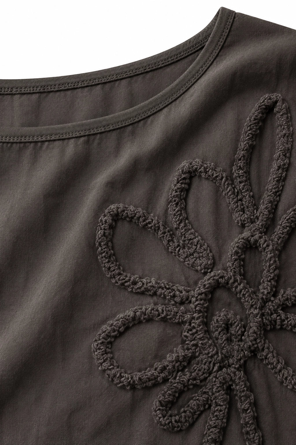 Close-up of a dark brown or charcoal gray top with a large textured floral applique on the chest.