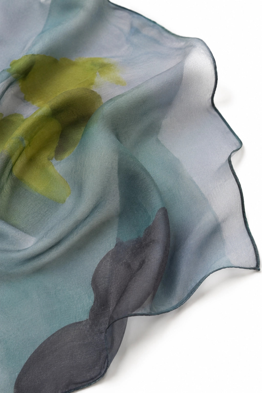 A sheer, lightweight scarf with a watercolor floral design in muted shades of blue-gray, olive green, and charcoal gray, draped elegantly on a white background.