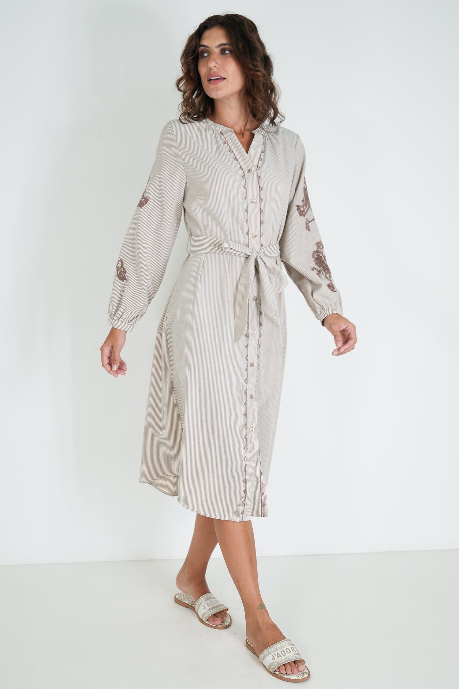 Woman wearing a beige dress with floral patterns on a white background