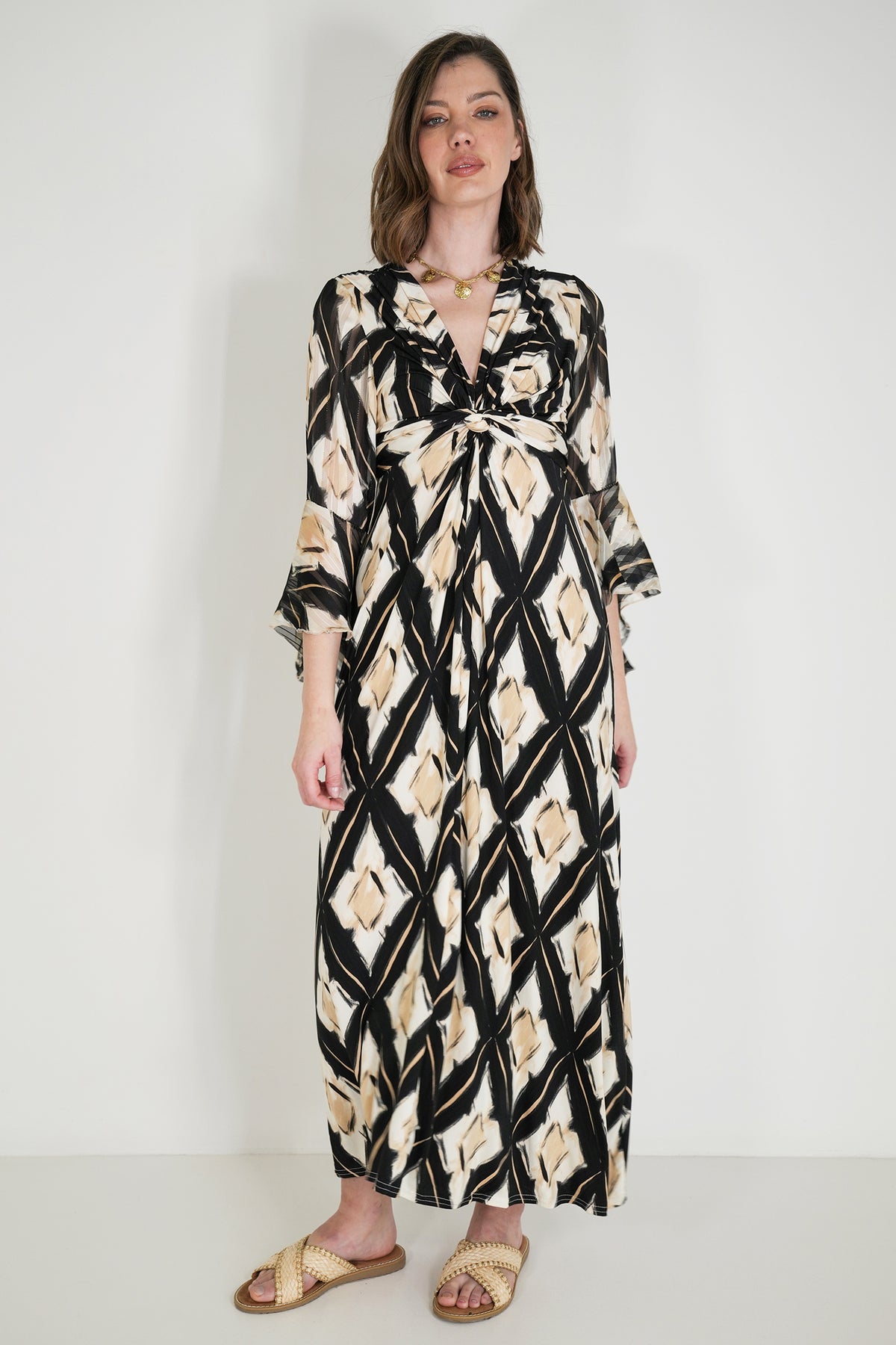 Woman wearing a long, patterned dress against a white background