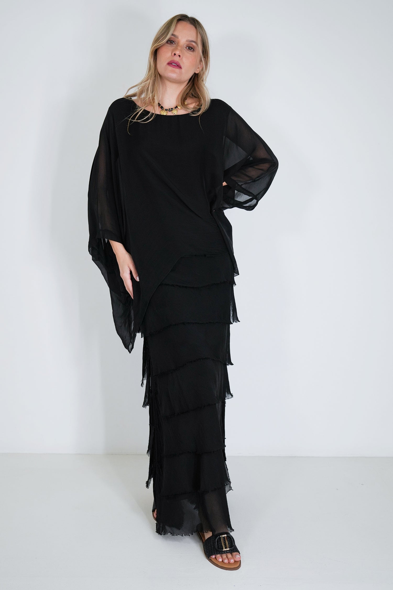 Woman wearing a black layered dress against a white background