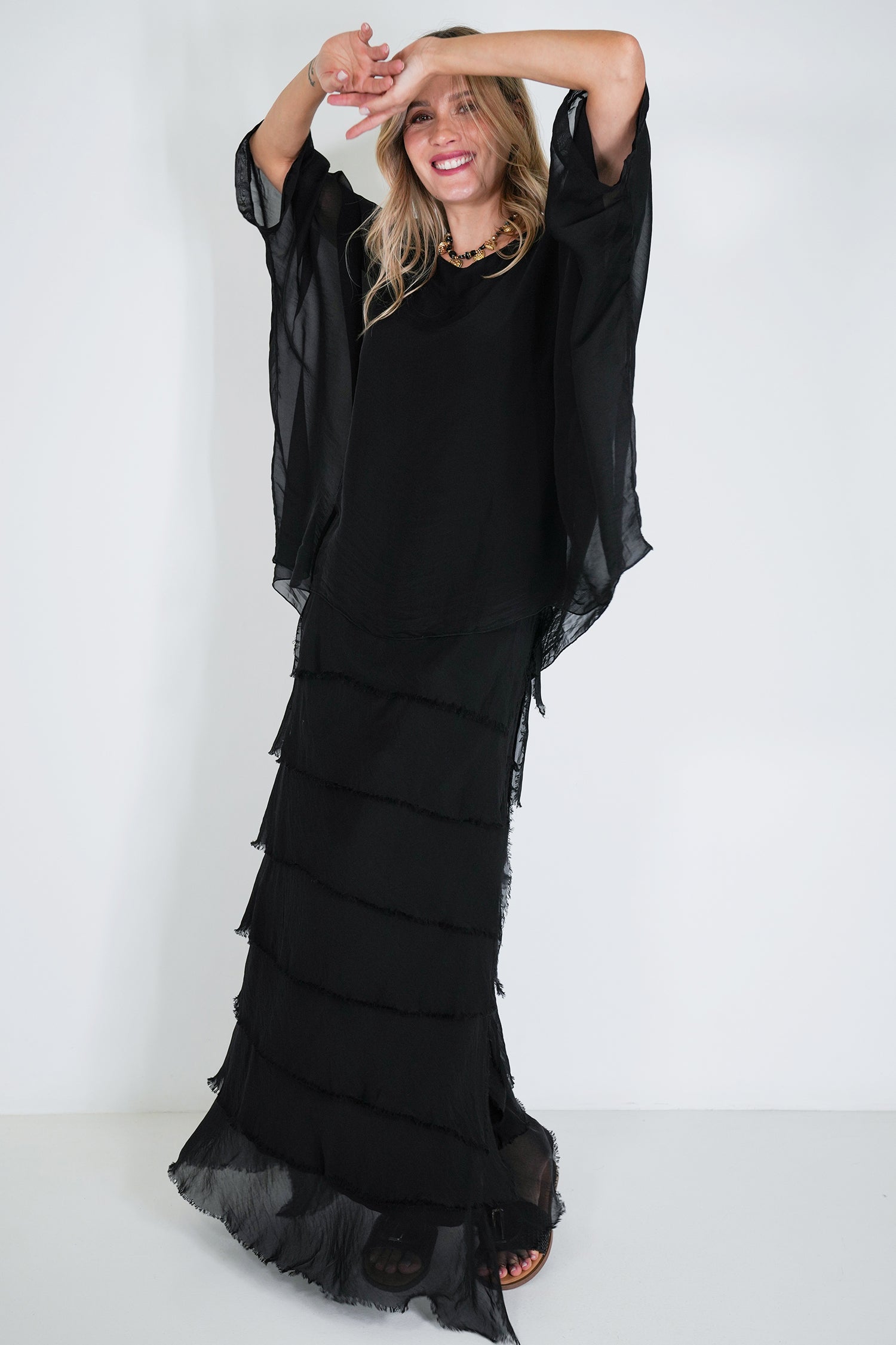 Woman wearing a black dress with ruffled layers on a white background