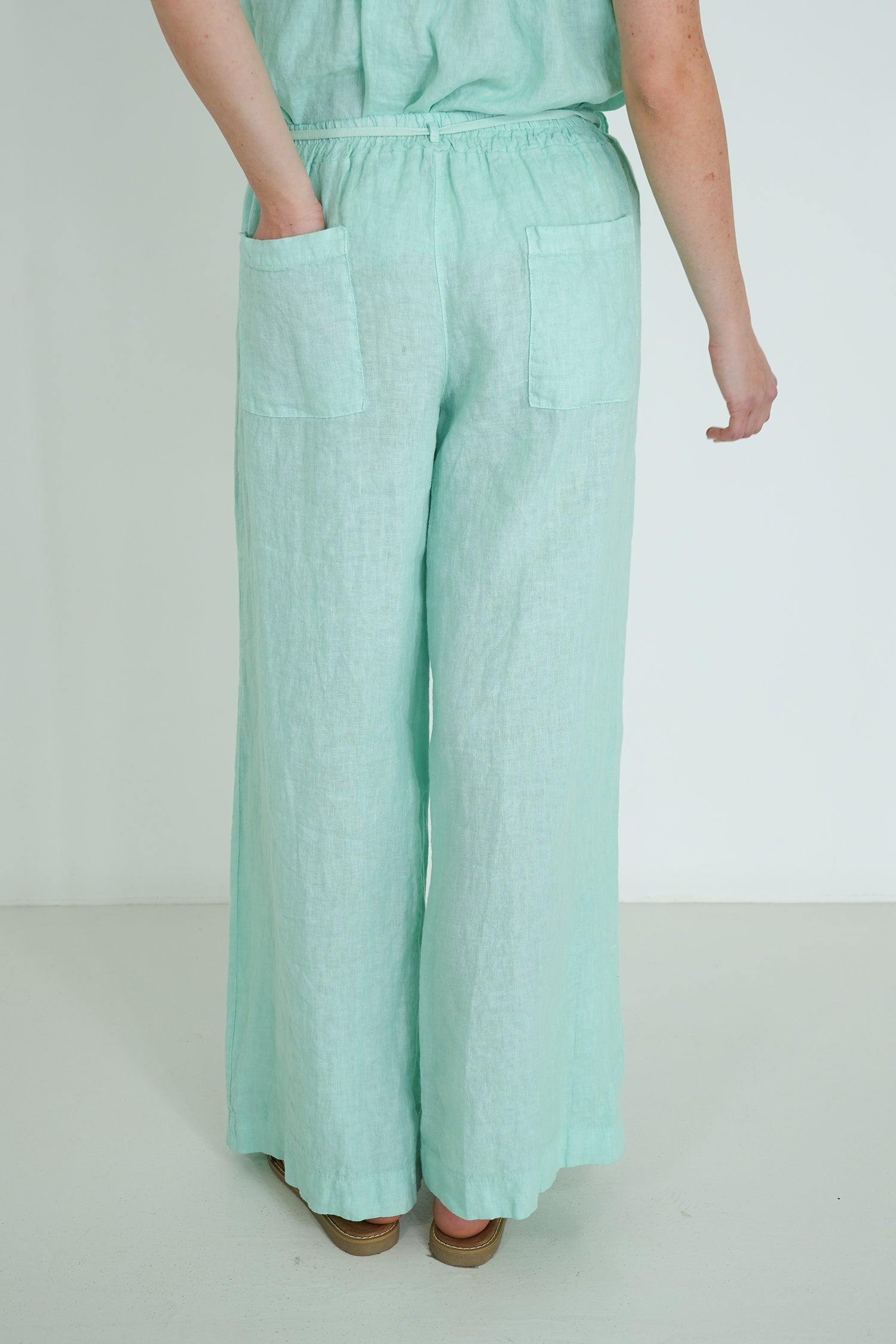Person wearing light green pants on a plain background