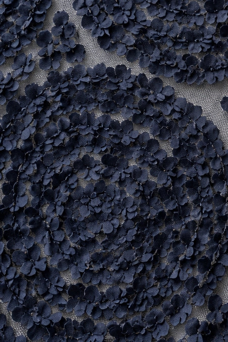 Close-up of a dark navy blue floral lace fabric with embroidered flower appliqués over a sheer mesh background.