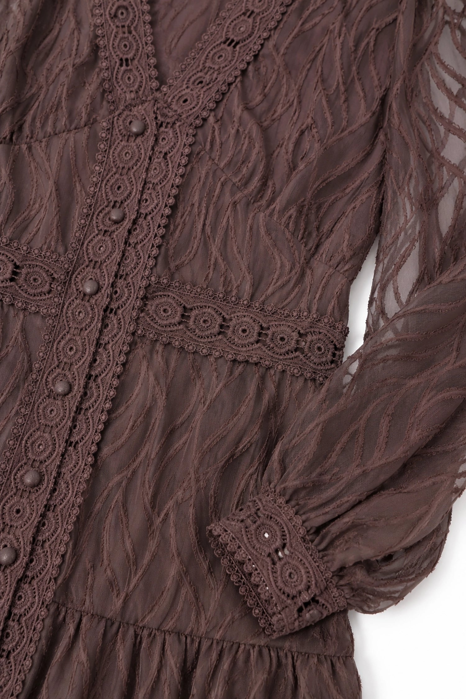 Close-up of a brown lace dress with intricate details on a white background