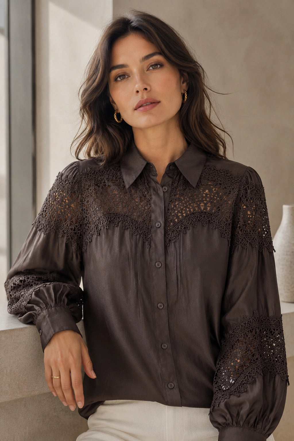 Woman wearing a dark blouse with lace details in an indoor setting