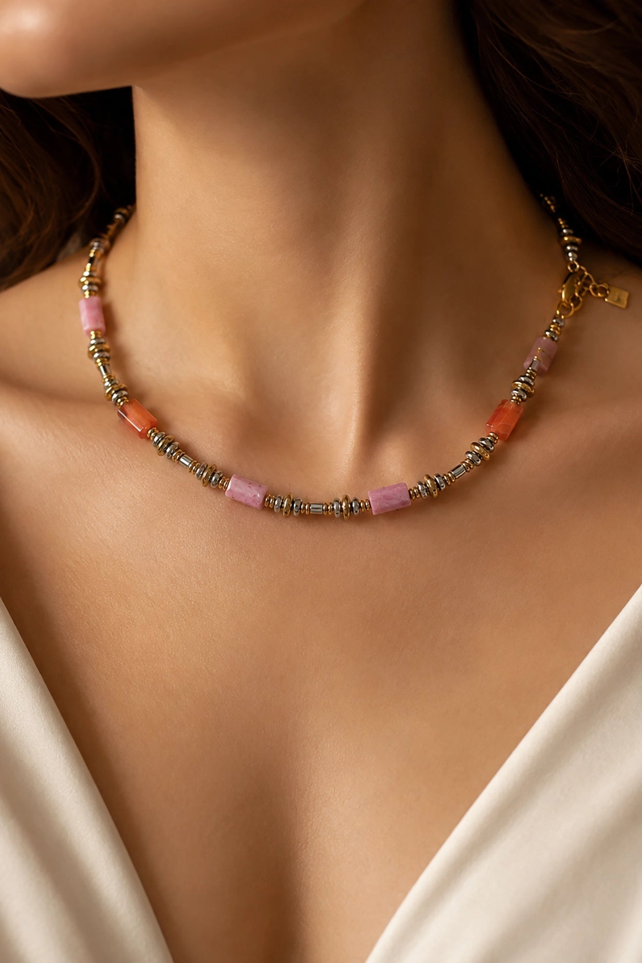 Necklace with pink and gold beads on a person wearing a white top