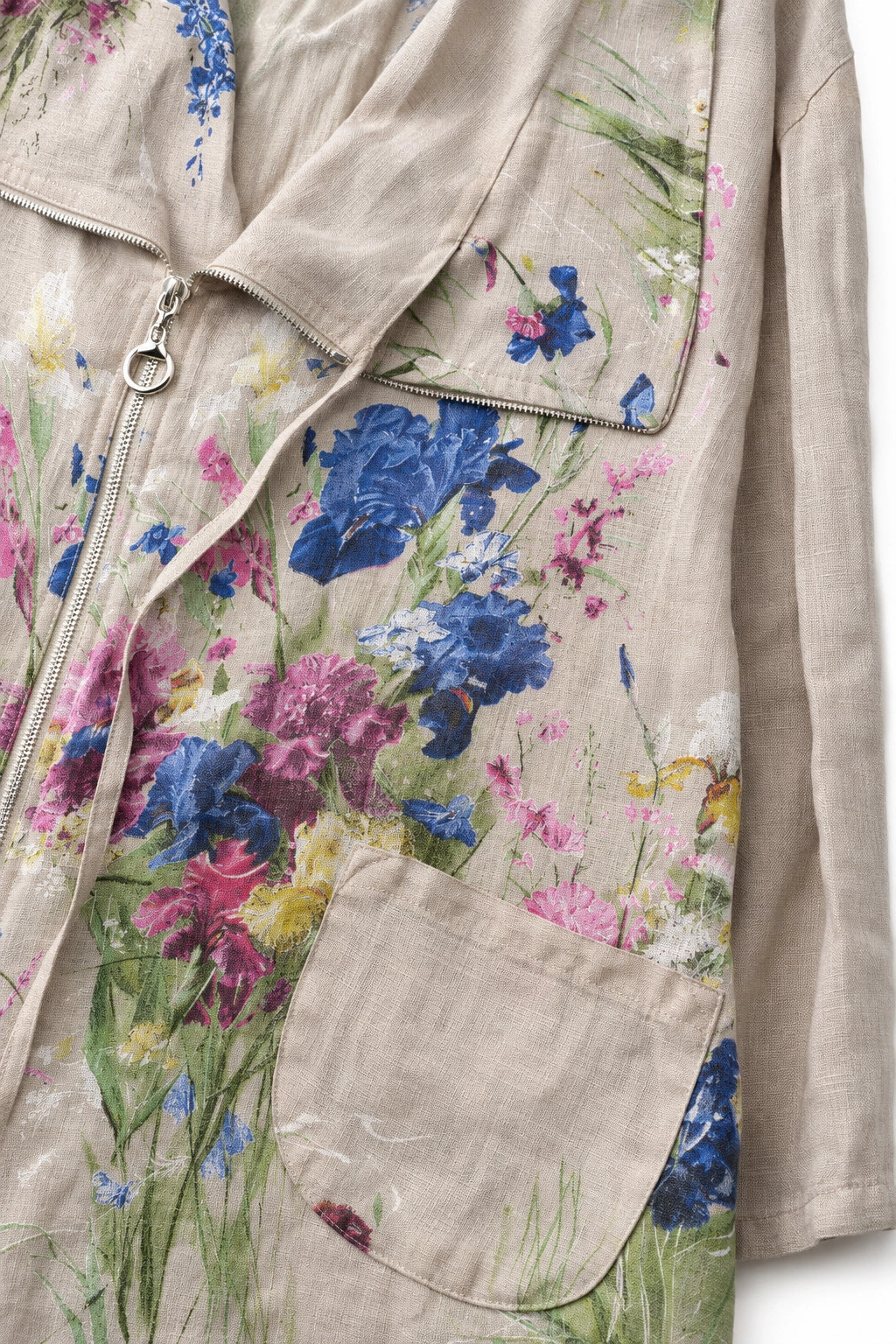 Close-up of a beige linen jacket featuring a colorful floral print with blue, pink, and purple flowers, a front zipper, and a pocket.