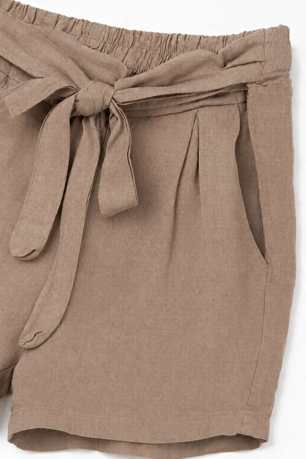 Close-up of taupe-brown linen shorts with a matching fabric tie belt at the elastic waistband.