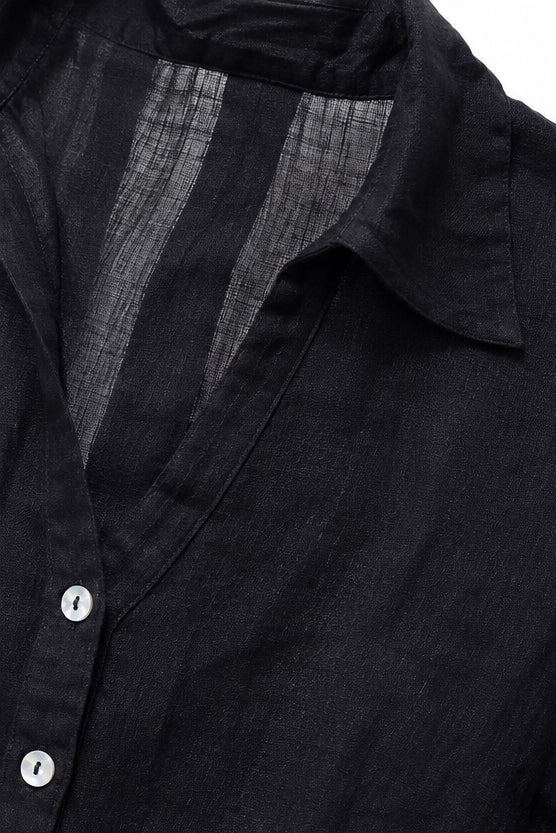 Close-up of a black button-front shirt with a pointed collar and visible textured inner lining.