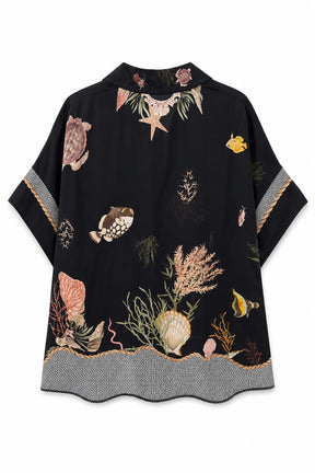 A black short-sleeve top featuring an all-over ocean-themed print with seashells, starfish, coral, and small yellow fish, finished with a gray patterned hem and sleeve cuffs.