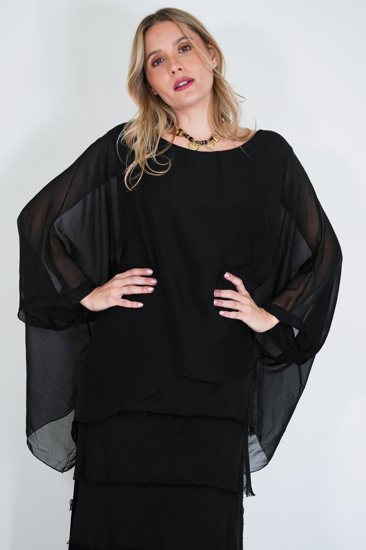 Woman wearing a black outfit with sheer sleeves against a white background