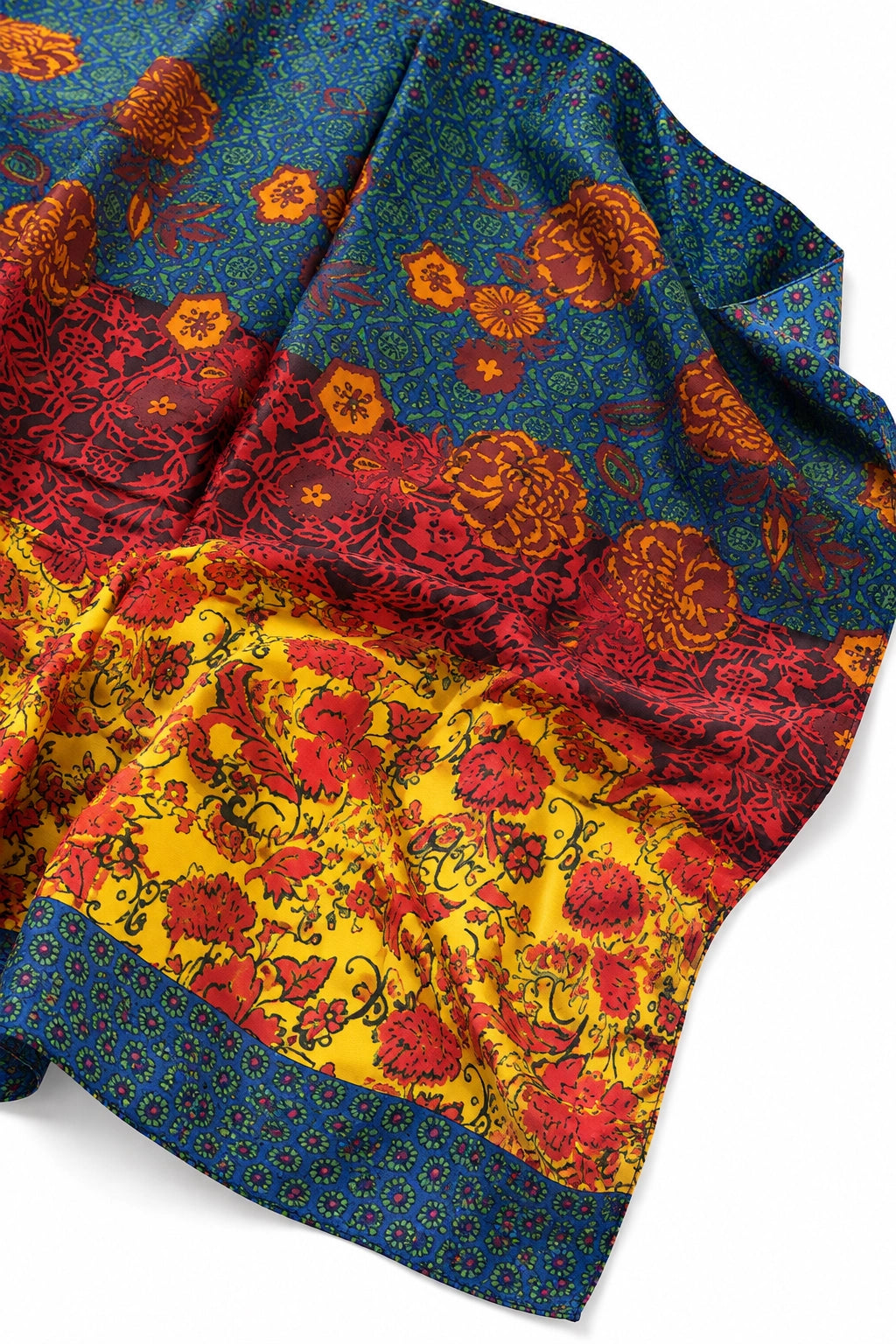 A folded patterned scarf or shawl with a rich floral print, featuring a dark blue upper section, a bright yellow lower section, and red and orange floral motifs throughout, finished with a blue patterned border.