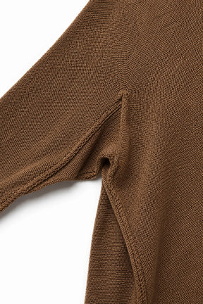 Close-up of a brown knit garment showing the sleeve seam and textured fabric against a white background.