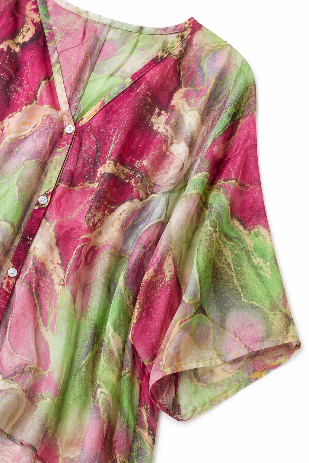 A close-up of a lightweight button-front top or tunic with a marbled abstract print in pink, green, and beige tones, shown against a plain white background.