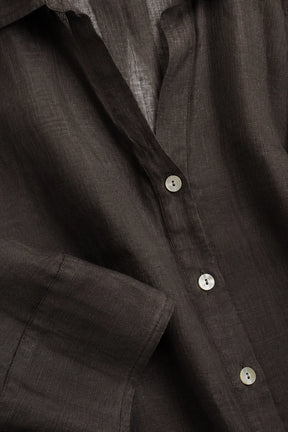 Close-up of a dark brown linen button-down shirt showing the textured fabric and white buttons.