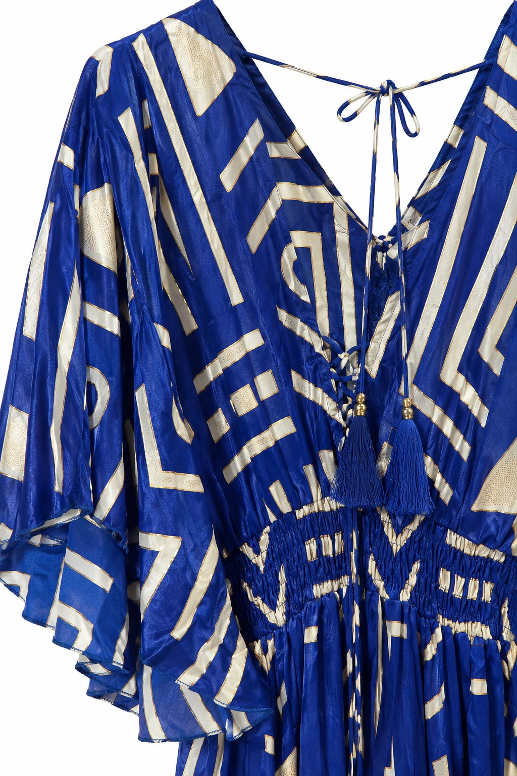 A blue and cream geometric print kaftan dress with a tie-neck design and tassel details, shown against a plain white background.