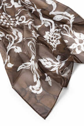 A sheer brown scarf with a white damask floral pattern, draped on a clean white background.