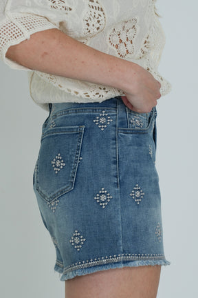 Denim shorts with decorative elements on a plain background