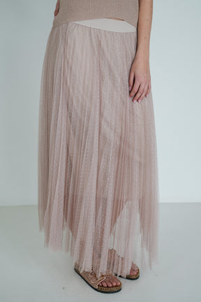 Person wearing a long, sheer pink skirt with a plain background