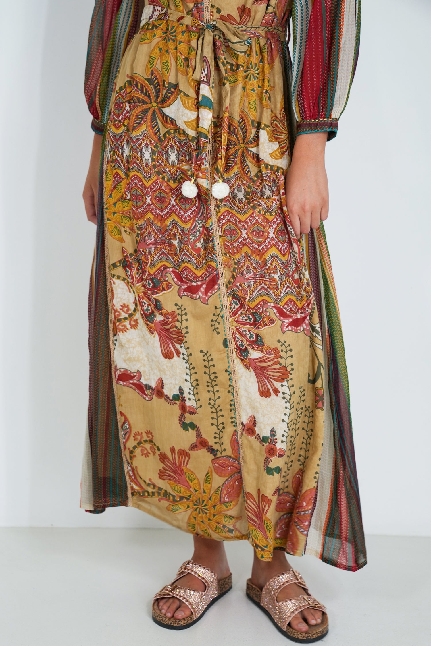 Person wearing a colorful patterned dress with a plain background