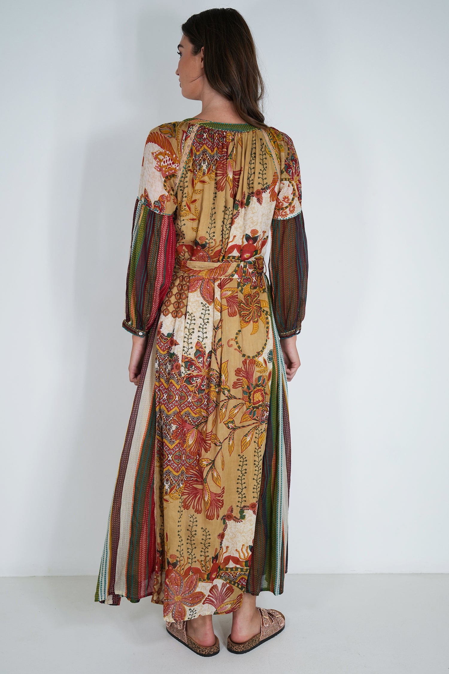 Woman wearing a long, patterned dress with a white background