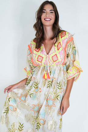 Woman wearing a colorful embroidered dress against a white background