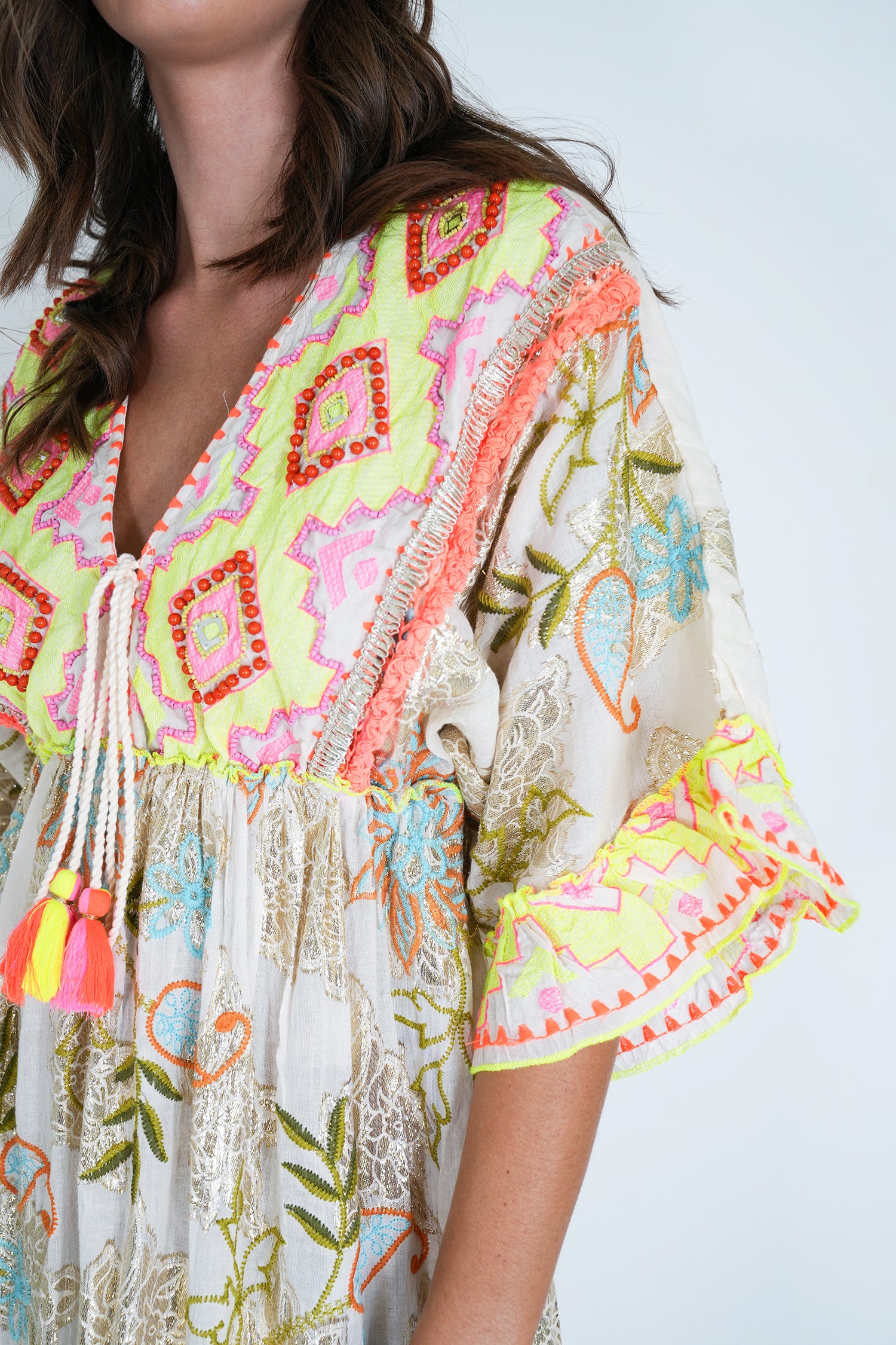 Colorful embroidered dress with tassels on a plain background