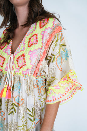 Colorful embroidered dress with tassels on a plain background
