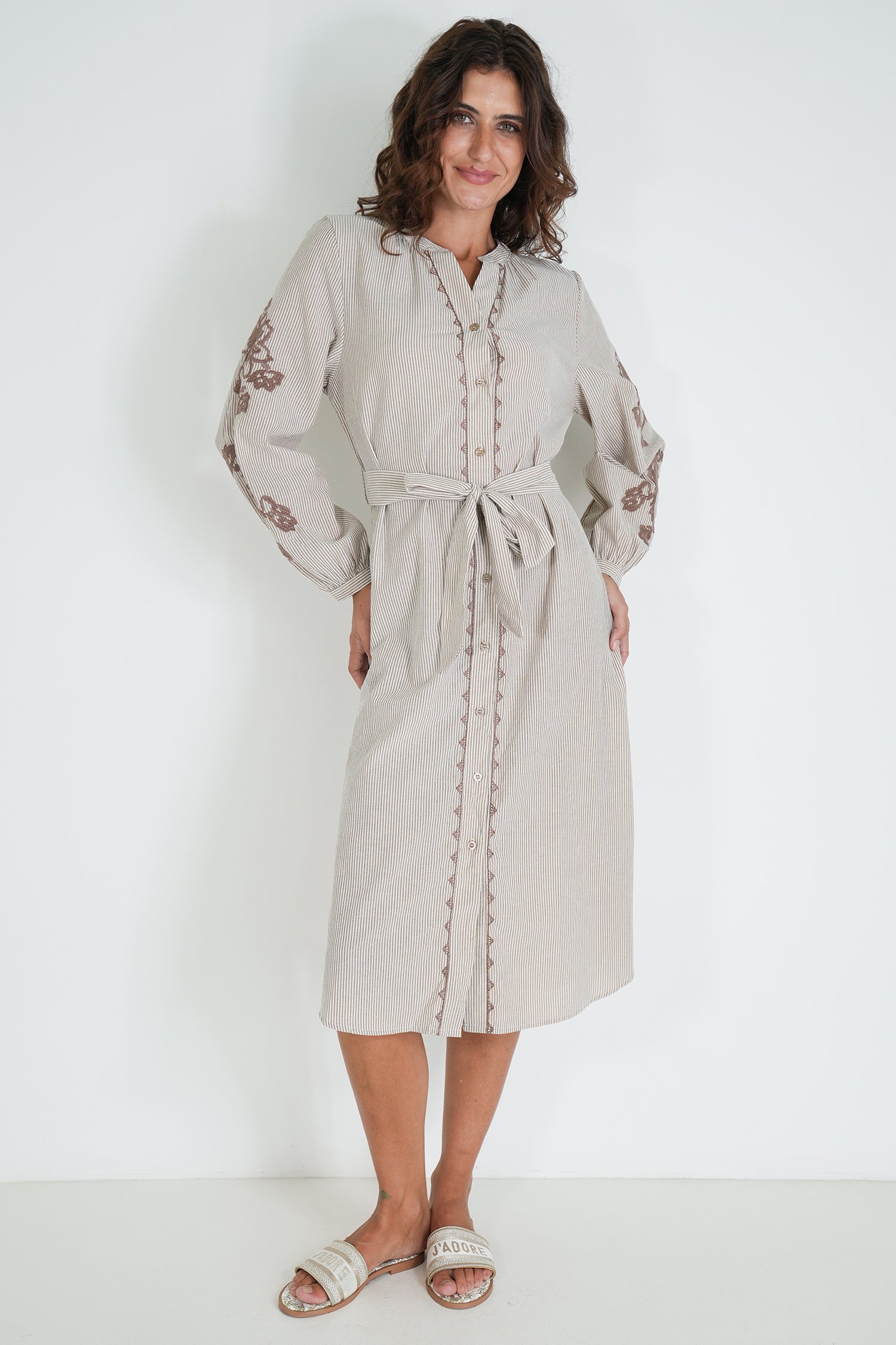 Woman wearing a beige dress with floral embroidery on a white background