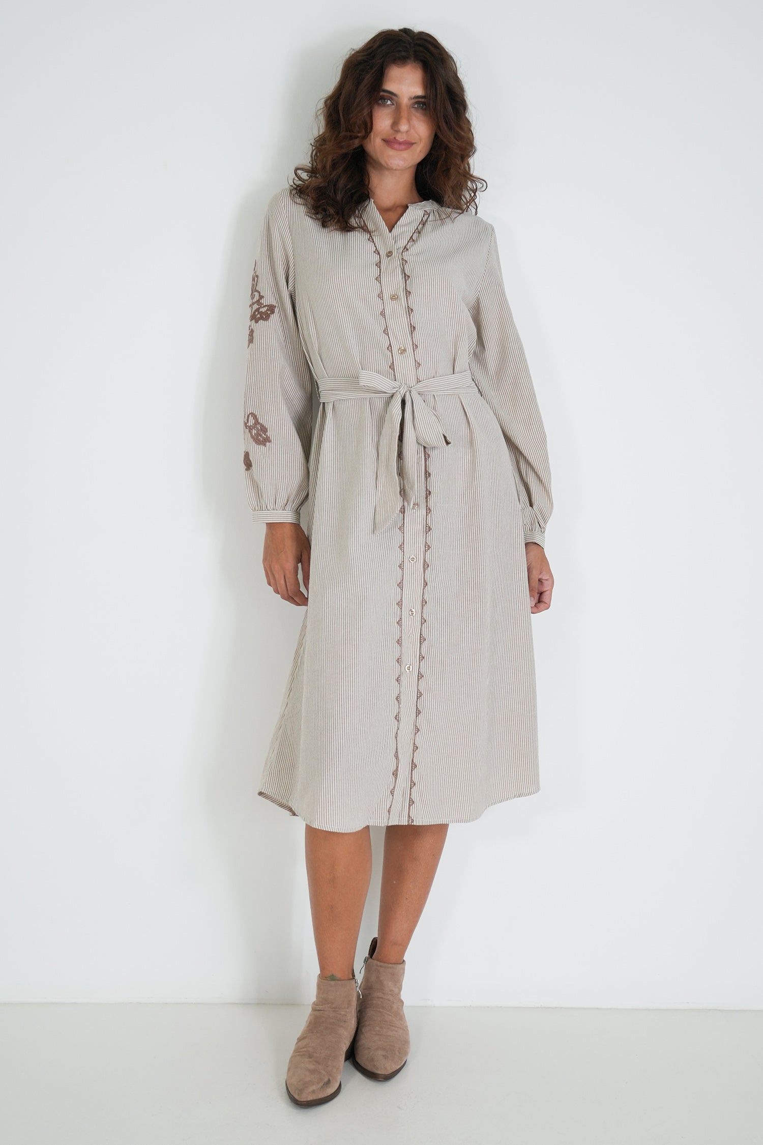 Woman wearing a beige dress with embroidery on a white background
