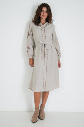 Woman wearing a beige dress with embroidery on a white background