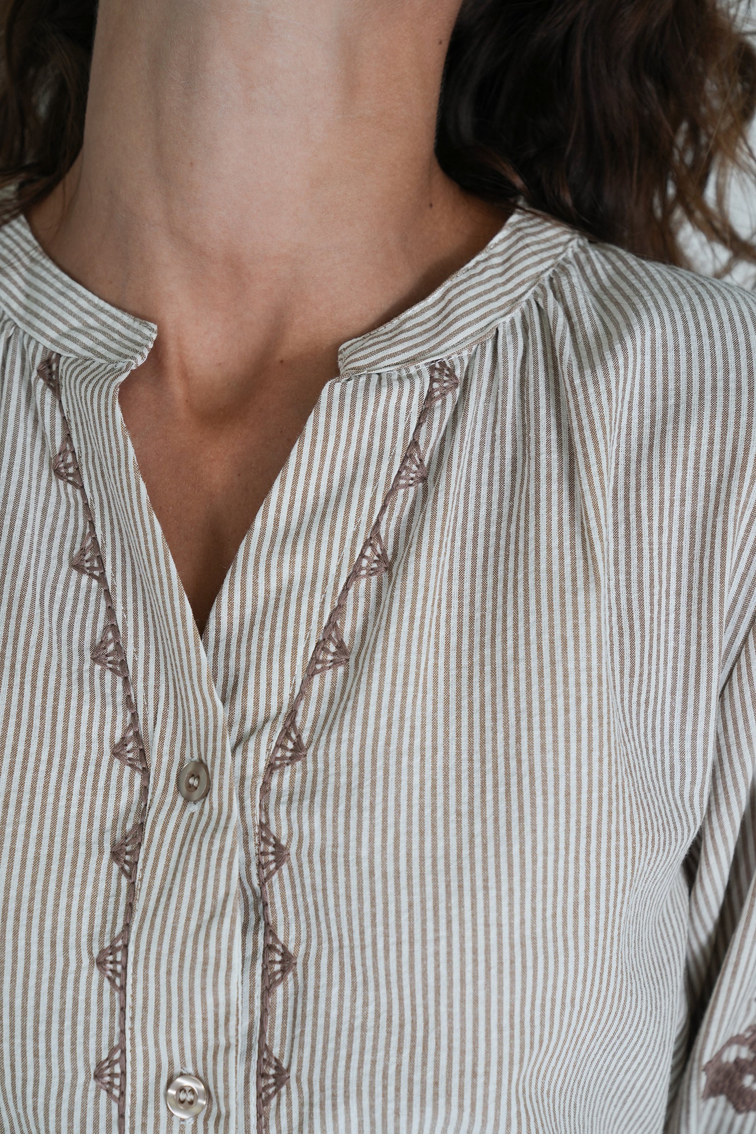 Close-up of a person wearing a striped shirt with intricate detailing.