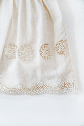 Close-up of a white fabric with lace detailing on a white background