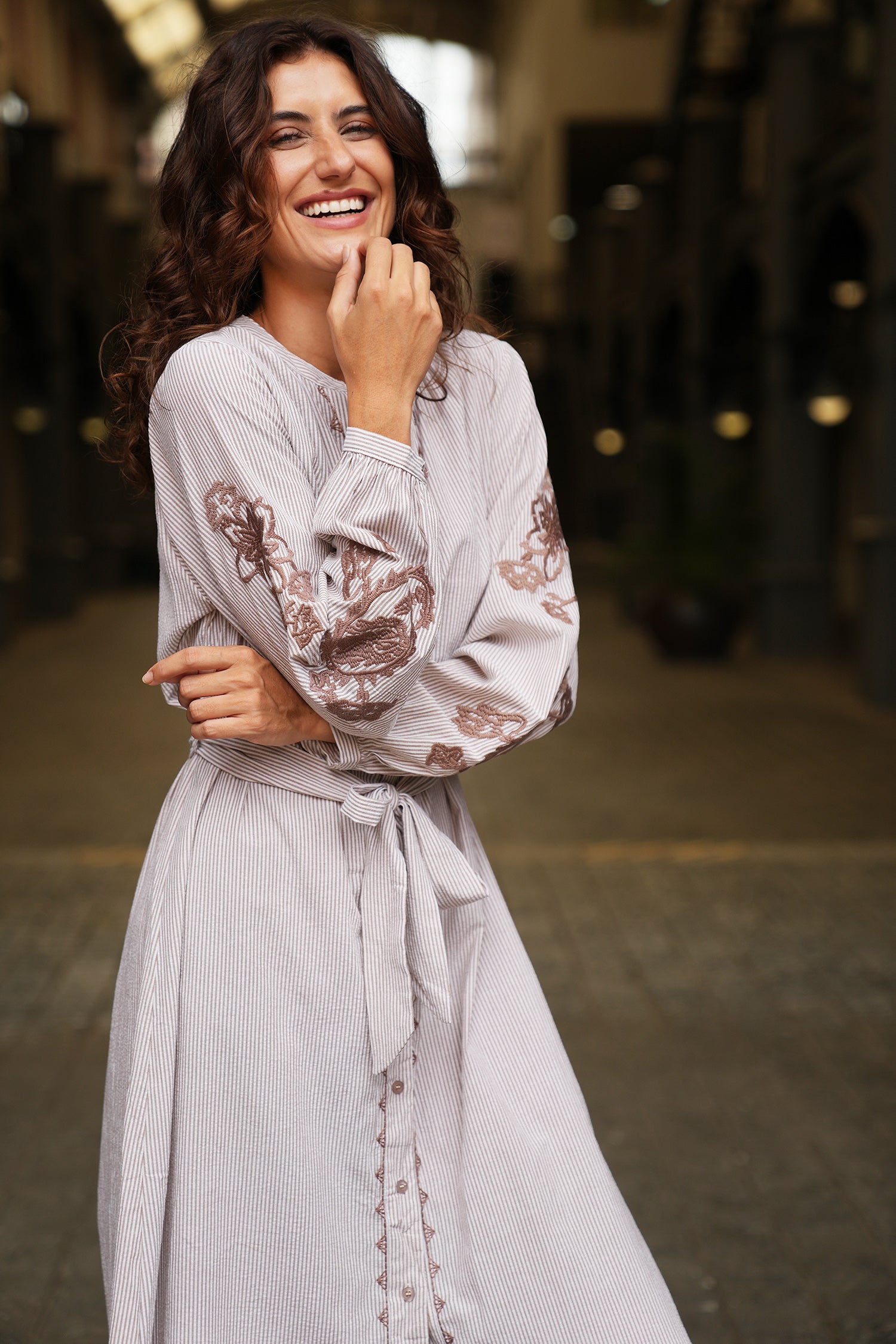 Woman wearing a light gray dress with lace details in an outdoor setting