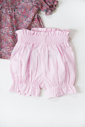 Pink shorts with a floral top on a white background