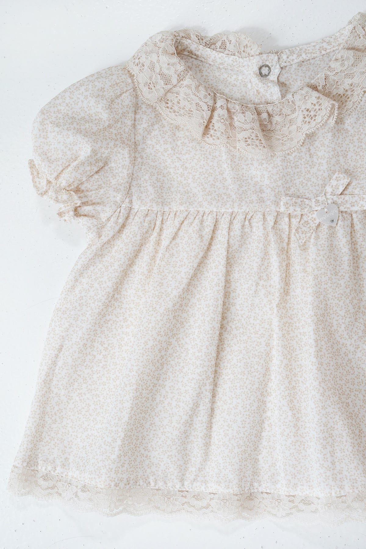 Beige baby dress with floral pattern on a white background