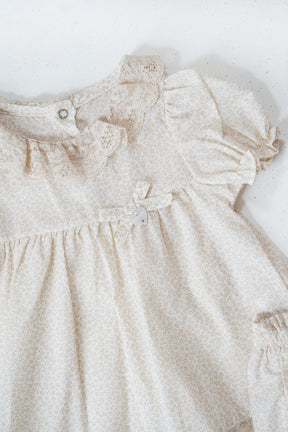 Beige baby dress with floral details on a white background
