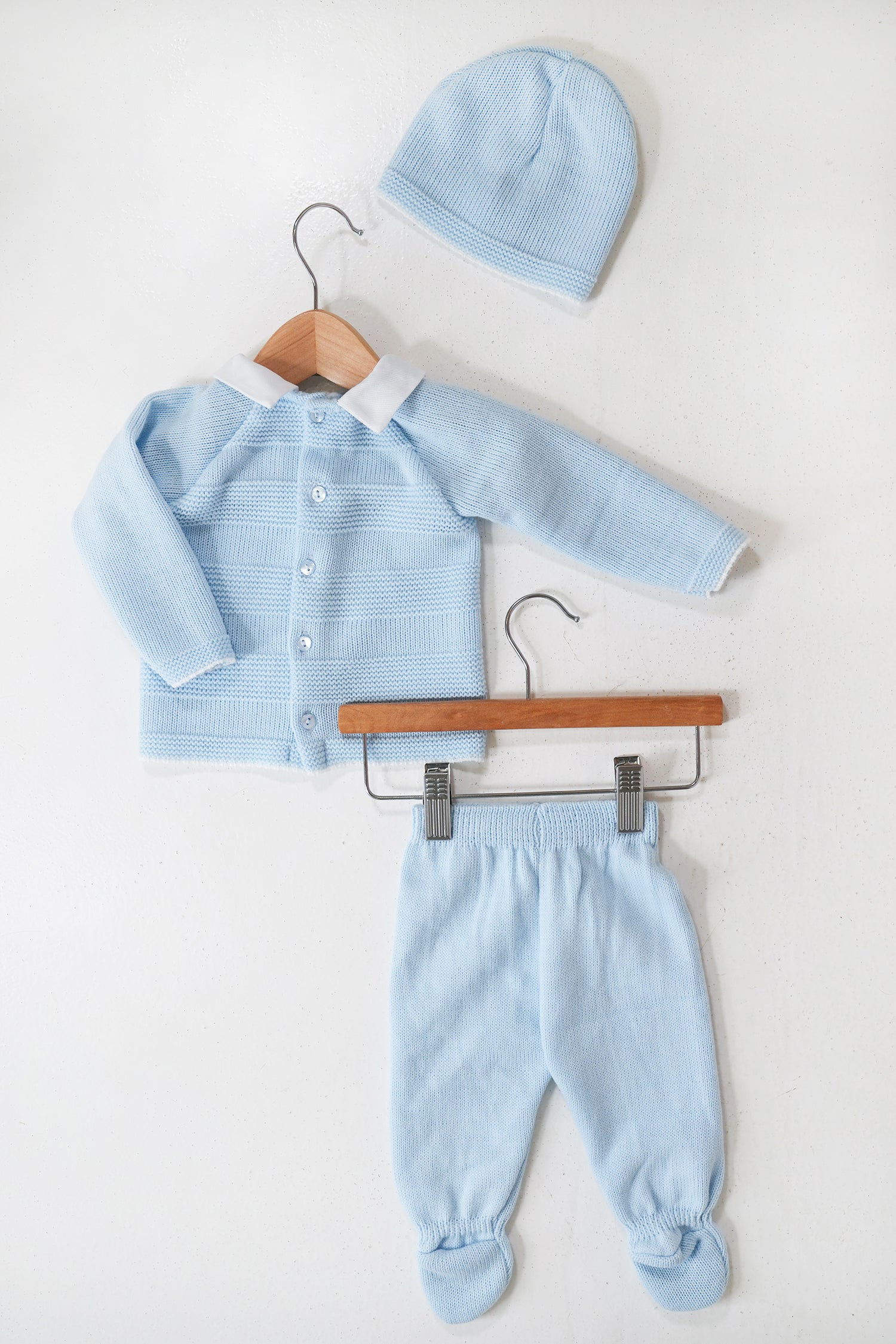 Baby blue outfit set with cardigan, pants, and hat on hangers against a white background