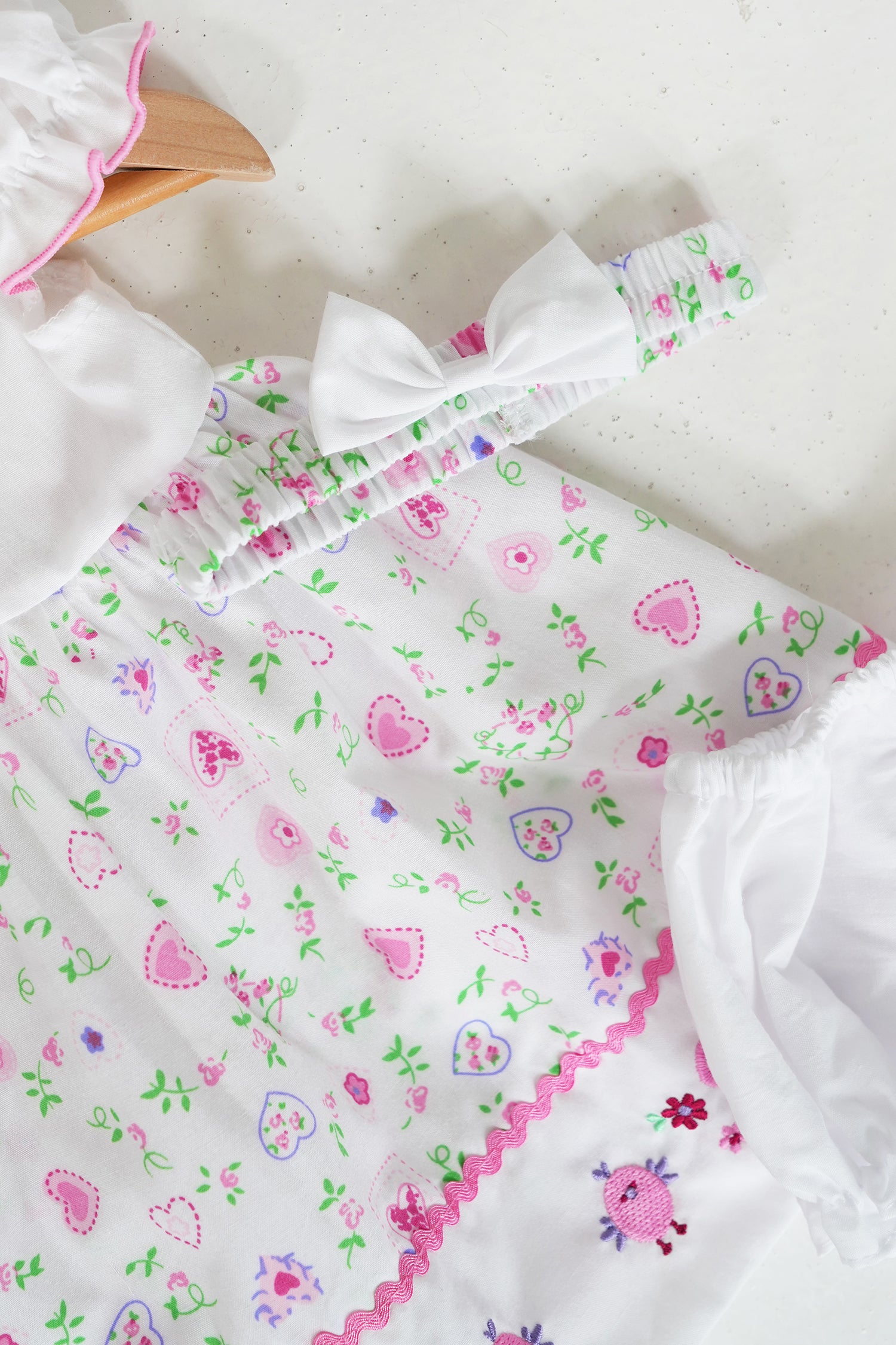 White Peggy baby dress with Peter Pan collar and pink heart floral print on hanger, Something Pretty