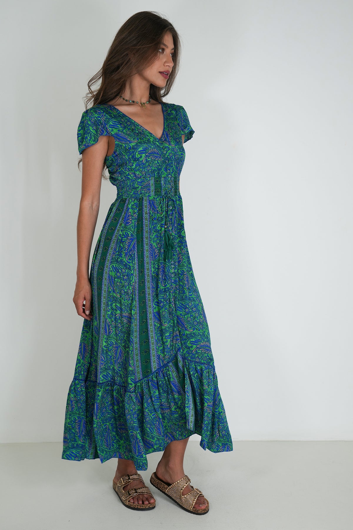 Woman wearing a green and blue patterned dress on a white background