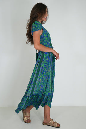 Woman wearing a green and blue patterned dress on a white background