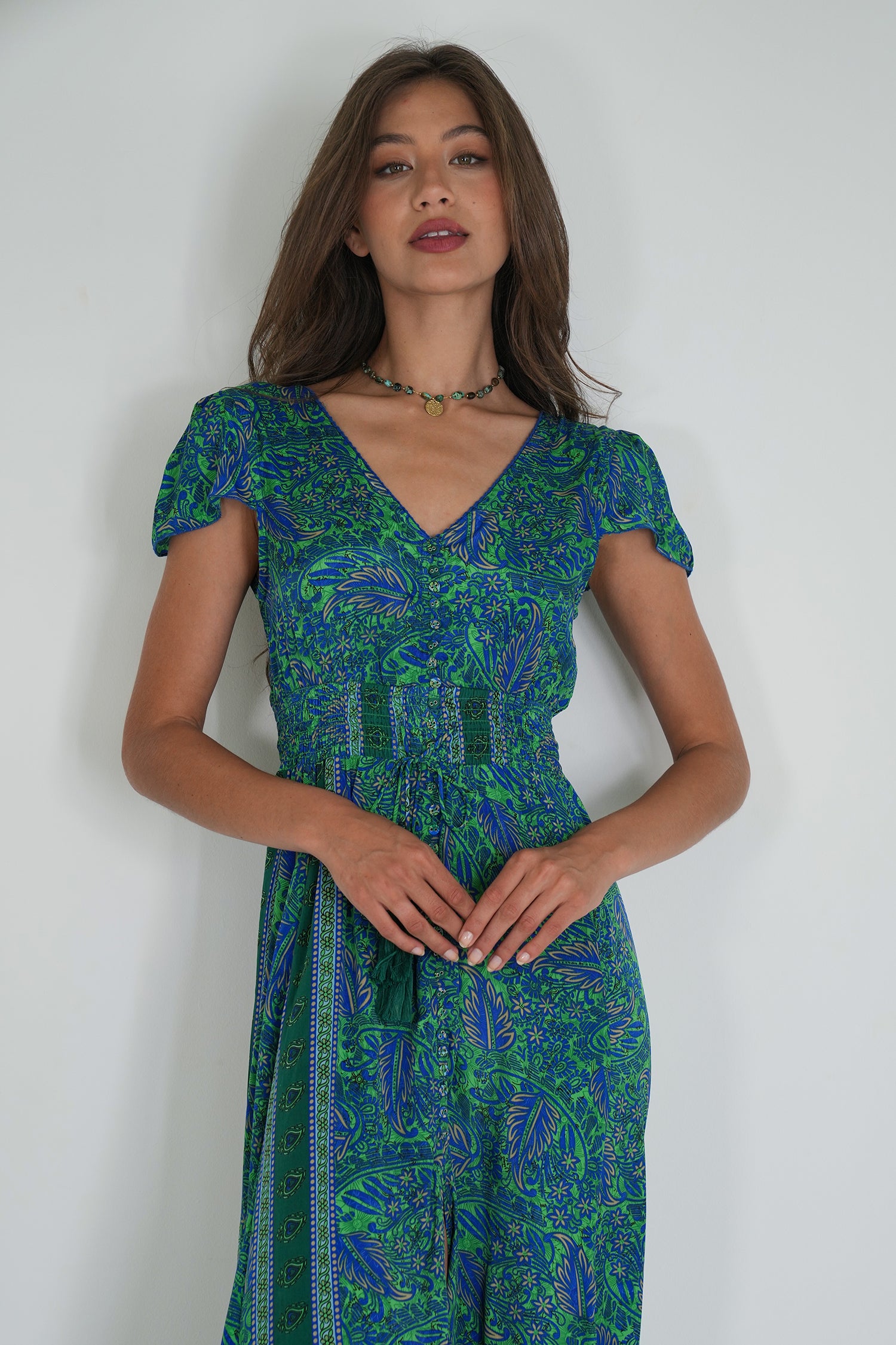 Woman wearing a green and blue patterned dress against a white background