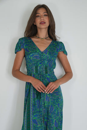 Woman wearing a green and blue patterned dress against a white background