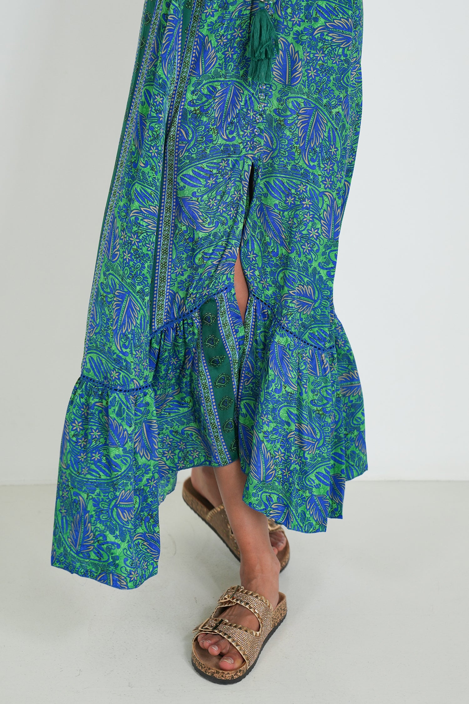 Green and blue patterned dress with a slit on a white background
