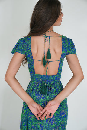 Woman wearing a green and blue patterned dress with an open back on a white background