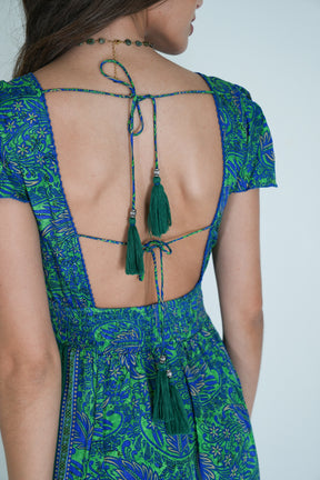 Green and blue patterned dress with open back and tassels on a plain background
