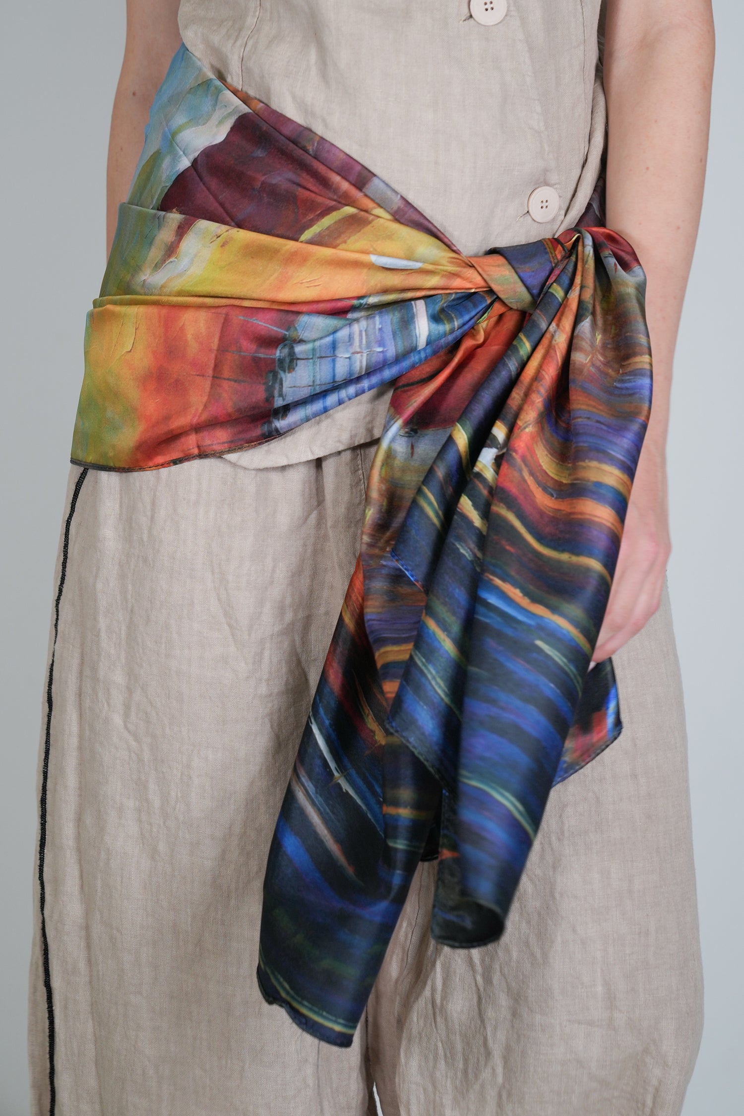 Person wearing a colorful scarf with abstract patterns on a plain background
