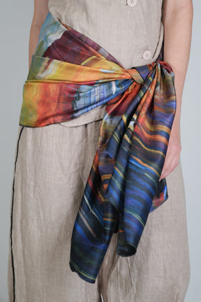 Person wearing a colorful scarf with abstract patterns on a plain background